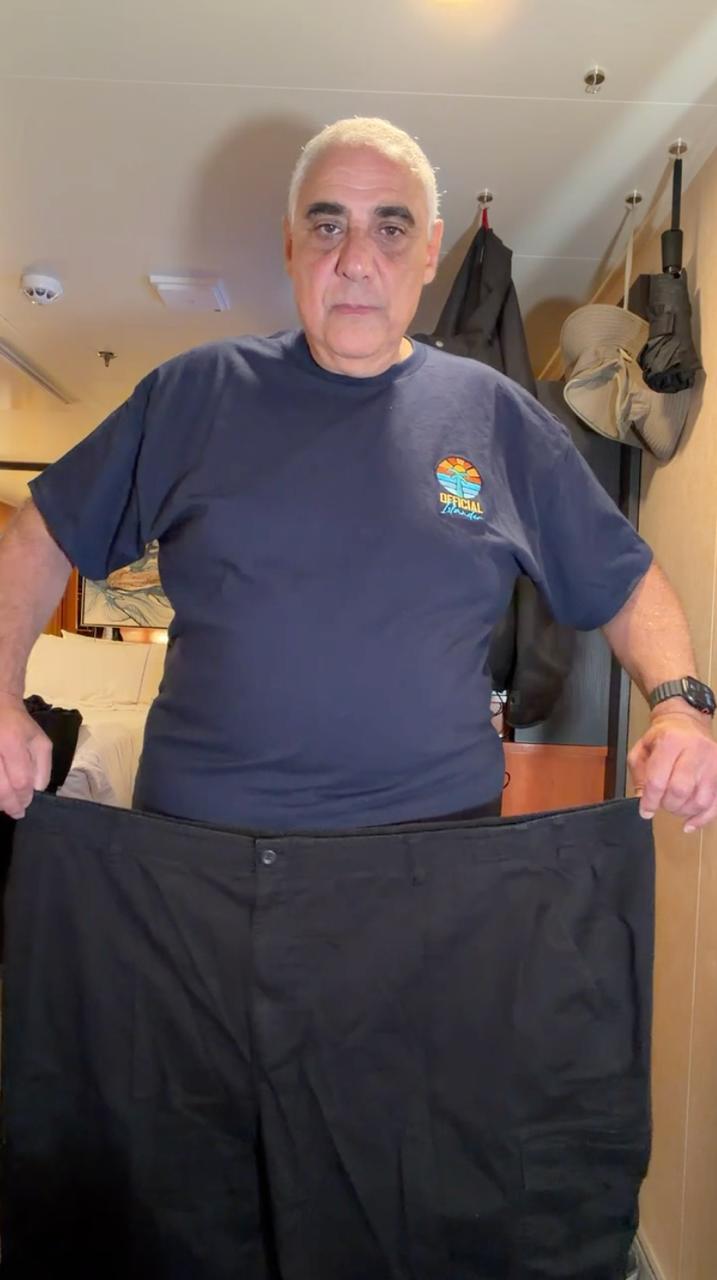 Samy holding up old oversized pants after weight loss